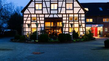 Ein traditionelles Fachwerkhäuschen mit symmetrischer Fassade, einem zentralen Eingang und einem gepflasterten Innenhof.