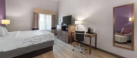 A hotel room with a bed, a desk, a chair, a television, and a mirror.