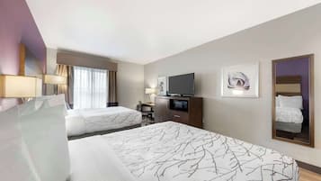 Habitación de hotel con dos camas, un escritorio, un televisor y un espejo.