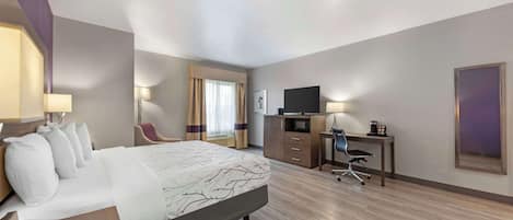 Habitación de hotel con una cama grande, un escritorio con computadora, una silla, televisor y teléfono.
