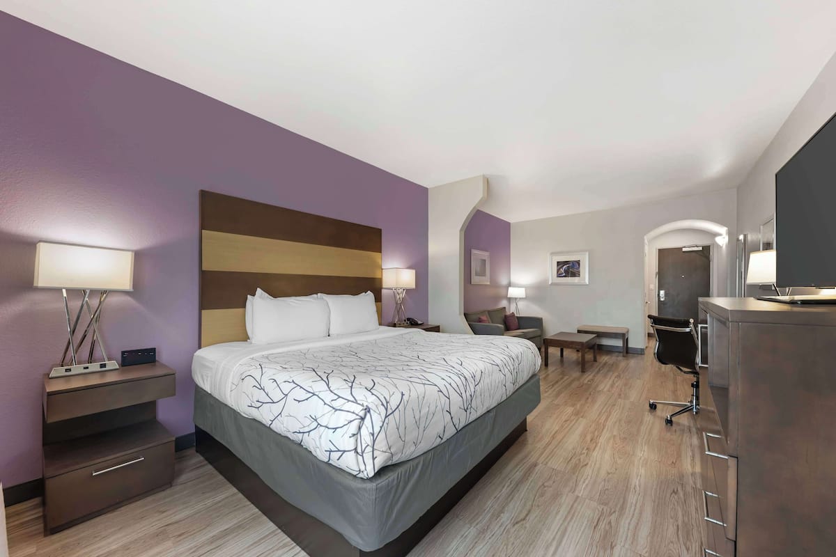 A hotel room with a large bed, bedside tables with lamps, a desk, and a chair.