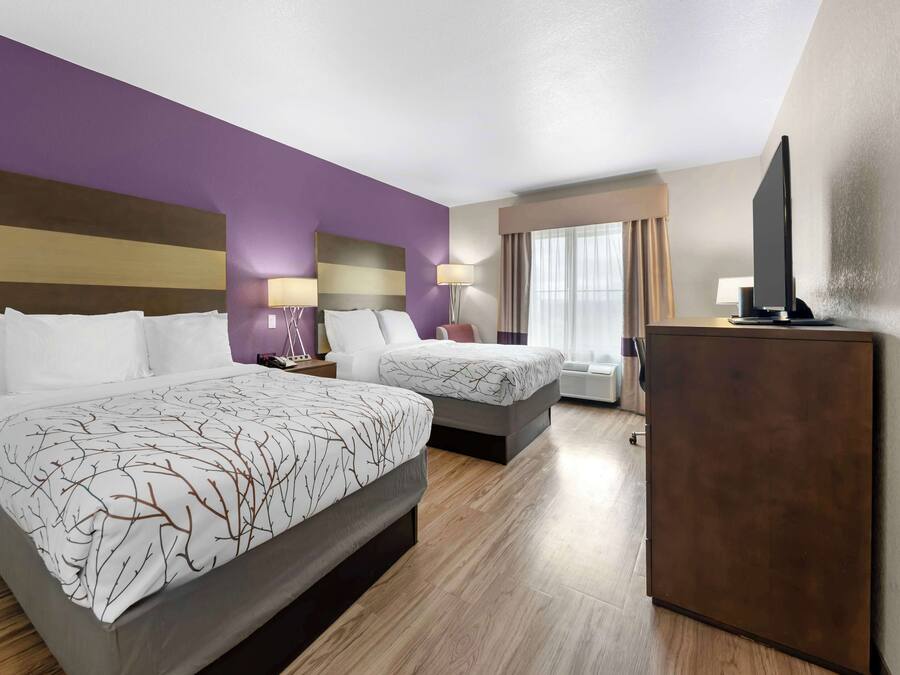 Habitación de hotel con dos camas, televisión y escritorio.