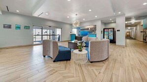 Een ruime lobby met een modern design, met een zithoek met banken en fauteuils, een centrale salontafel en een decoratieve kroonluchter.