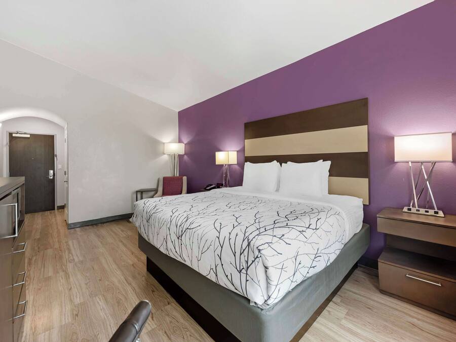 Ett modernt hotellrum med en stor säng, sänglampor, ett skrivbord och en garderob.