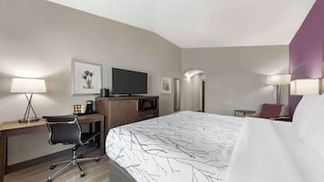A hotel room with a bed, desk, chair, TV, and lamps.