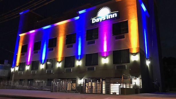 Een Days Inn gebouw met een bord, meerdere ramen en een hekwerkentree.