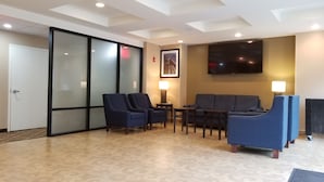 Een hotel lobby met een zithoek, een flatscreen televisie aan de muur en een deur met geëtste glaspanelen.