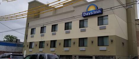 A hotel with a sign reading 'Days Inn,' featuring a beige exterior, multiple windows, and a gated entrance.