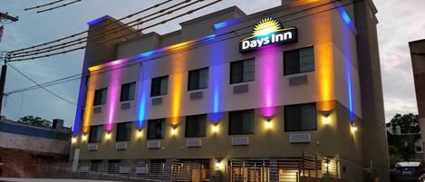 A Days Inn building with a modern facade, multiple windows, and a visible entrance with a gated driveway.