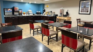 Een restaurant met tafels en stoelen, een toonbank met een koffiemachine, en een bord waarop 'Daybreak' staat.