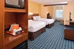 A hotel room with two beds, a desk, a TV, and a microwave.