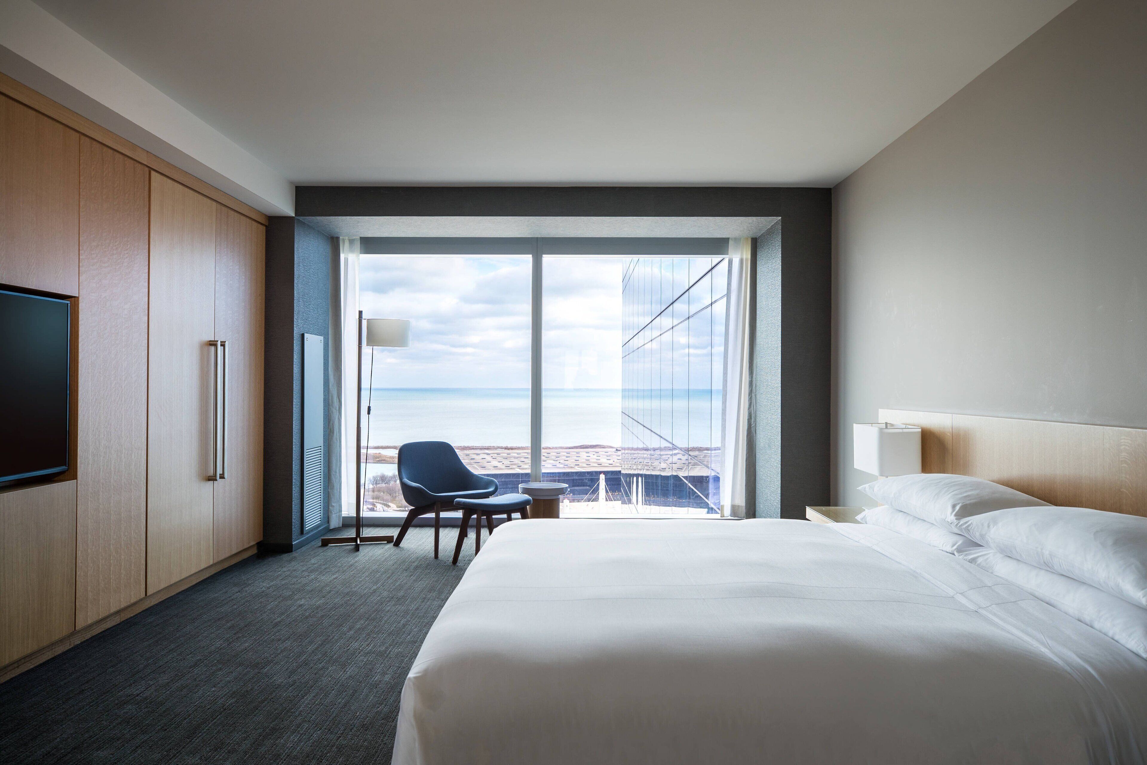 Habitación de hotel con una cama grande, un escritorio, una silla y un televisor.