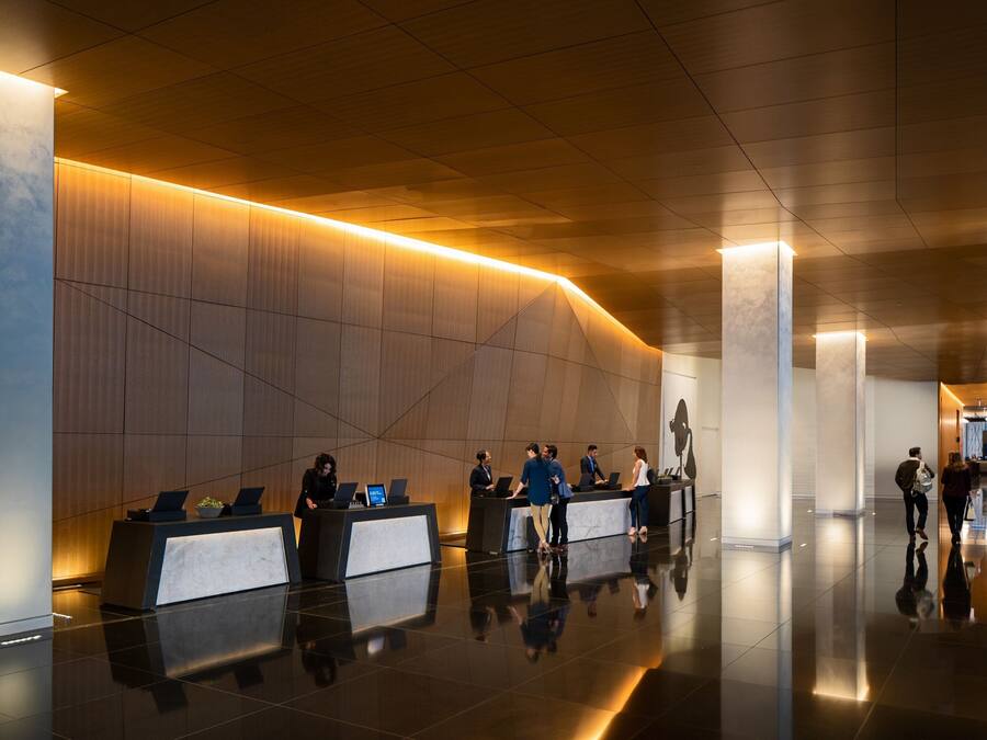 Um lobby moderno com balcão de recepção, teto alto e piso lustroso.