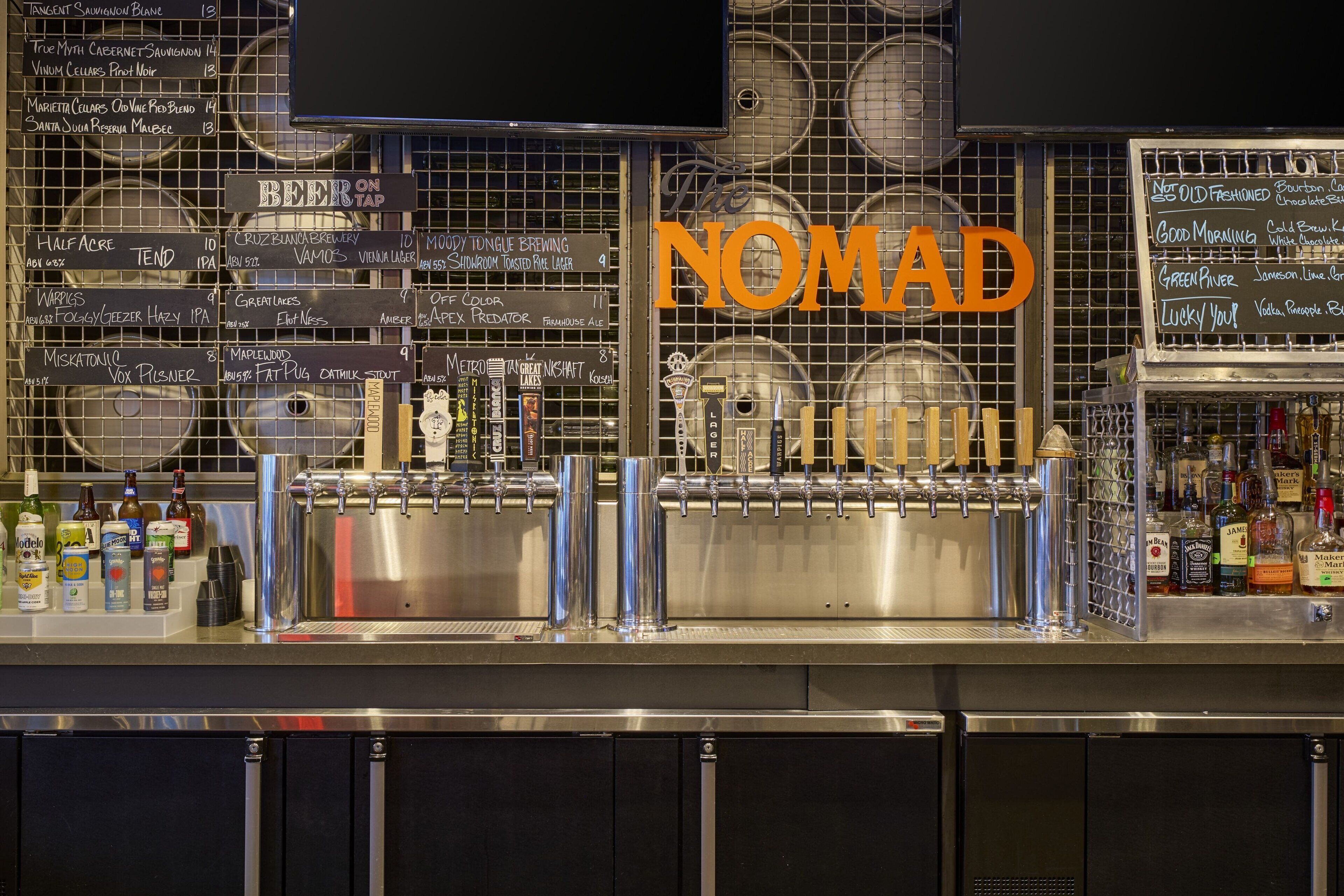 Un espace bar équipé d’un système de tirage à la pression et d’un tableau affichant une sélection de bières et de cocktails.