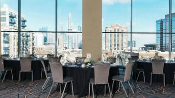 Un salón de conferencias con mesas dispuestas para una reunión, amplias ventanas con vistas a la ciudad.