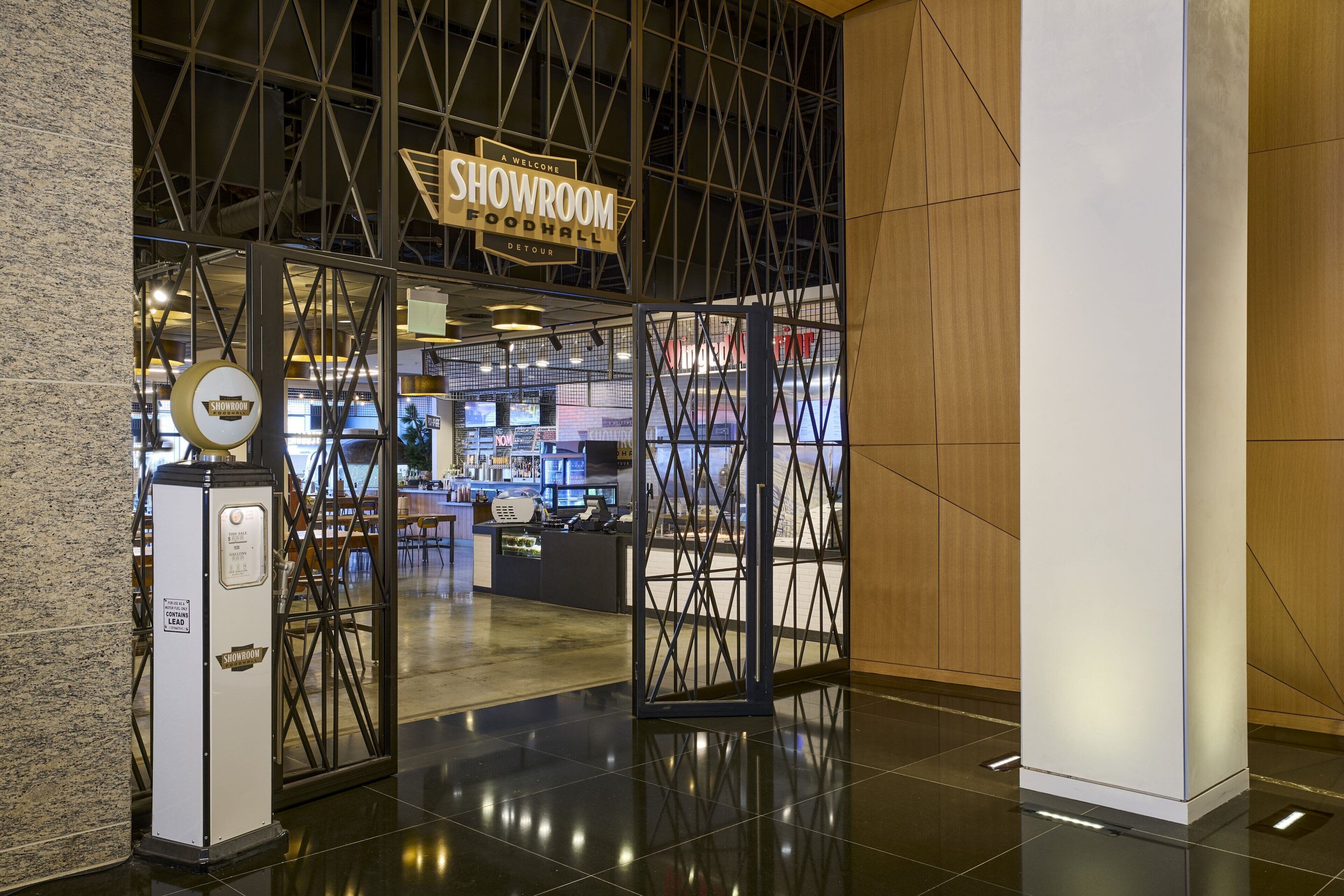A modern hotel entrance with a glass door leading to a reception area.