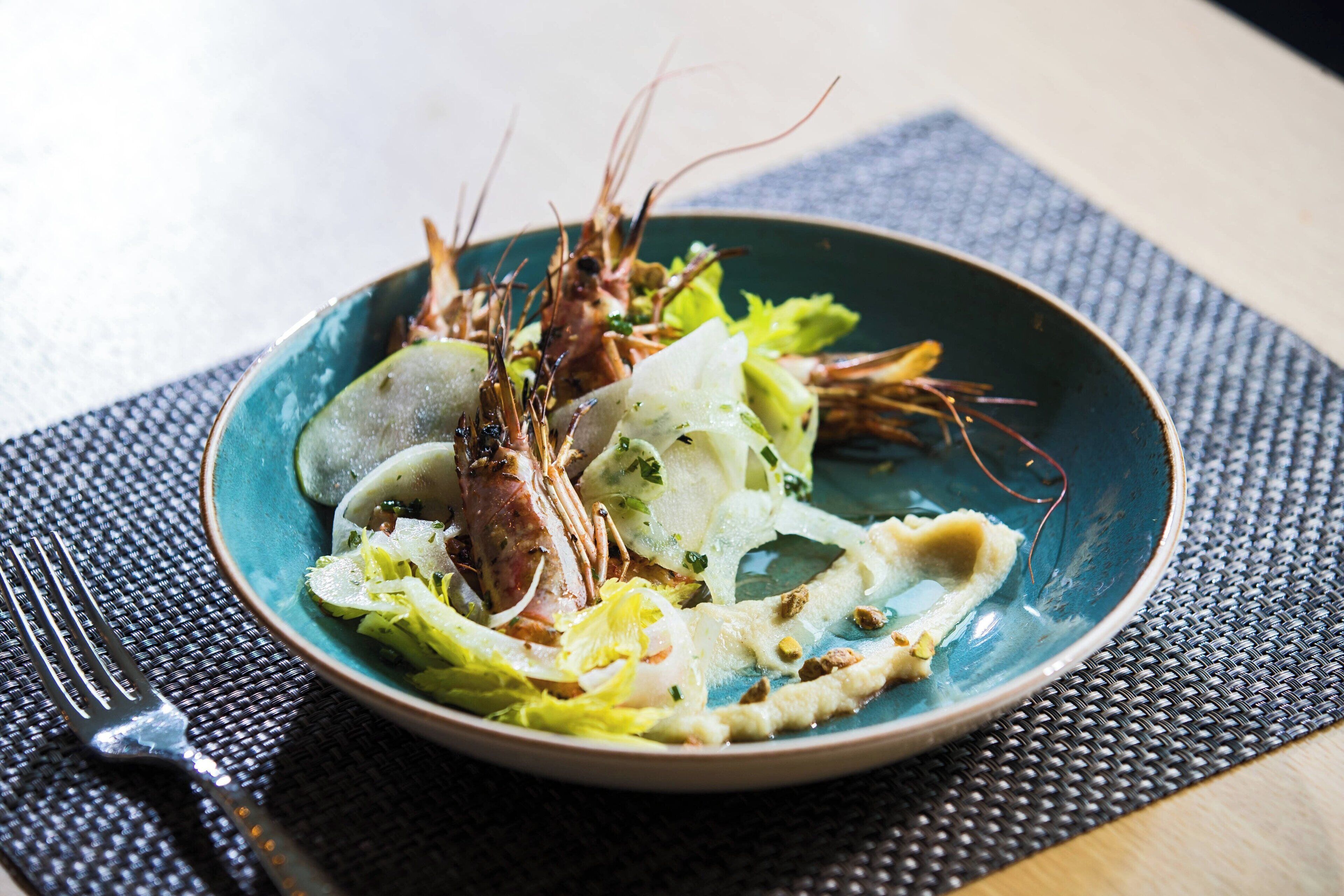 Un plato de comida con mariscos y verduras sobre un plato azul.
