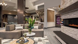 A modern lobby with a sectional sofa, a round coffee table, a fireplace, and a reception desk. - Residence Inn by Marriott Boise Downtown City Center (Boise)