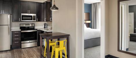 A compact hotel room with a kitchenette, a bed, and a bathroom.