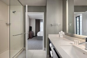 Spacious room with a large bathroom, glass shower, and a comfortable bed.