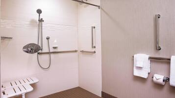 A bathroom with a shower, grab bars, a toilet, and a towel rack.