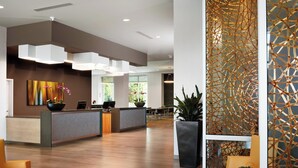 Un área de recepción moderna con suelo de madera, un mostrador de recepción y zonas de estar.