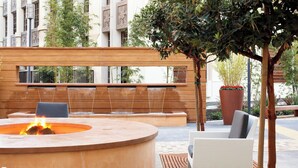 Un espacio de estar al aire libre con forma circular, que incluye un hogar y está rodeado por un muro de madera y una planta en maceta.