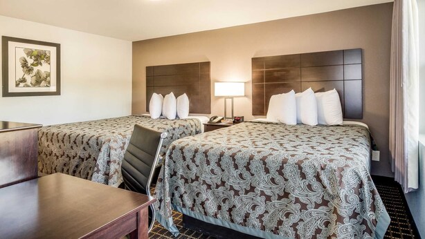 A hotel room with two beds, a desk, and a chair. - Rodeway Inn Middleboro - Plymouth (Middleborough)