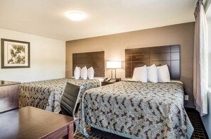 Habitación de hotel con dos camas, un escritorio y una silla.