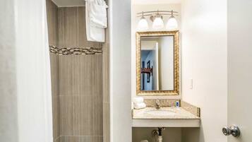 A bathroom with a shower, a sink, and a mirror.