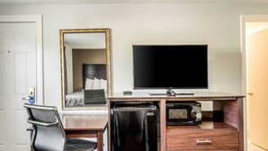 A hotel room with a desk, a chair, a television, a refrigerator, and a microwave. - Rodeway Inn Middleboro - Plymouth (Middleborough)