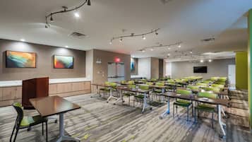 A conference room with tables and chairs, a podium, and a television screen.