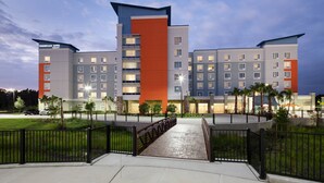 Un hôtel à plusieurs étages au design moderne, caractérisé par un mur d’accent de couleur orange très visible et un toit plat.
