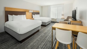 Een hotelkamer met twee bedden, een bureau, een stoel, een televisie en een raam met gordijnen.