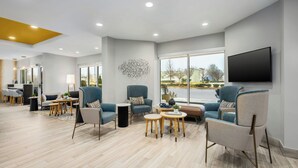 Een ruime, moderne lounge met comfortabele zithoek, een flatscreen televisie en grote ramen met uitzicht op het omliggende landschap.