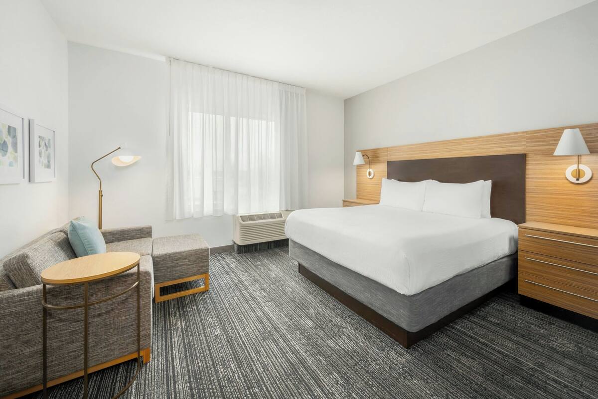 Een hotelkamer met een groot bed, een bank, een klein rond tafeltje en een lamp.