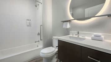 Un baño moderno con bañera, inodoro y tocador con espejo.
