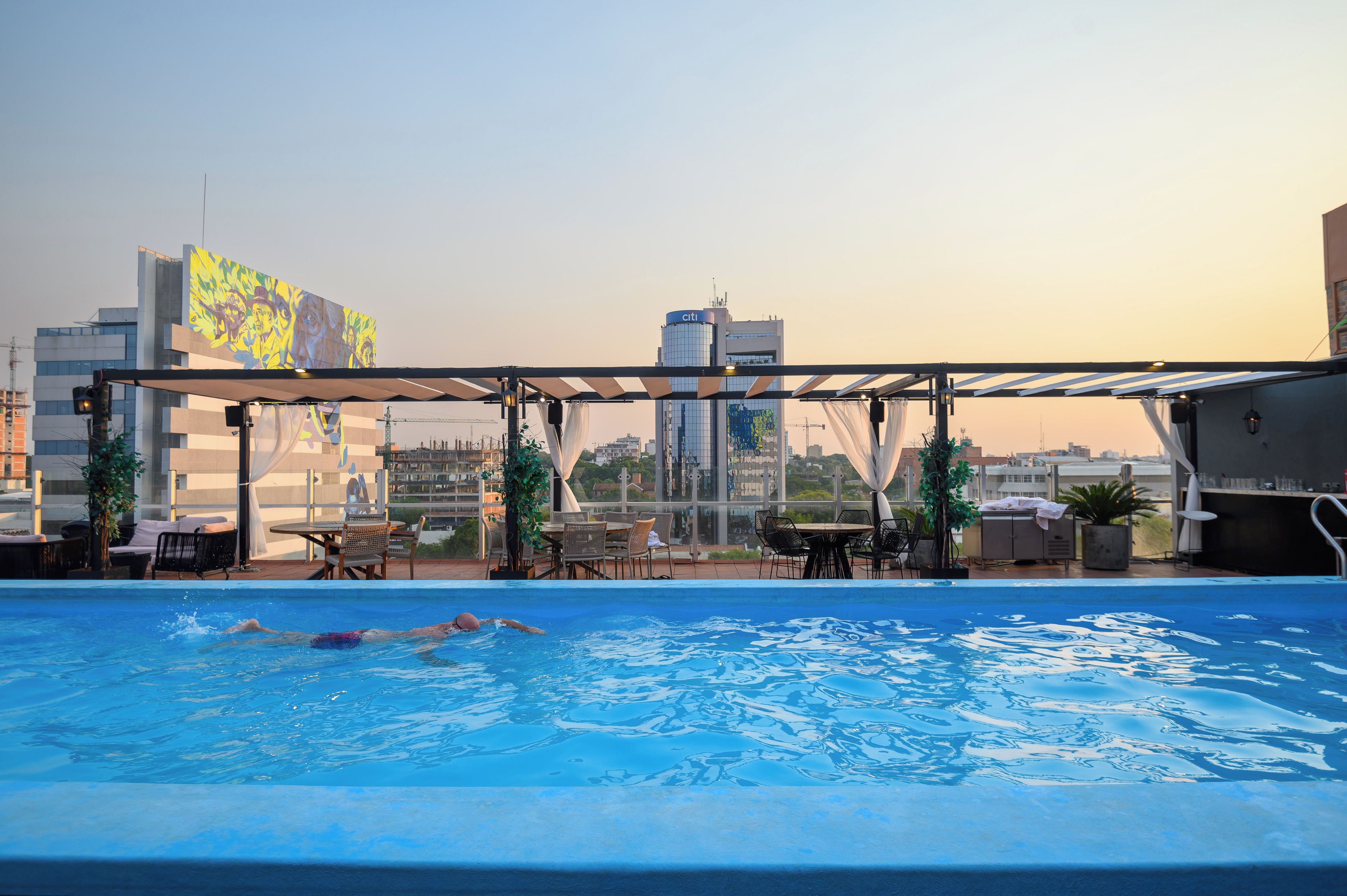 Piscina no terraço com vista para o horizonte da cidade, incluindo um edifício com o letreiro 'citi'.