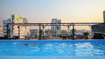 Piscina no terraço com vista para o horizonte da cidade, incluindo um edifício com o letreiro 'citi'.