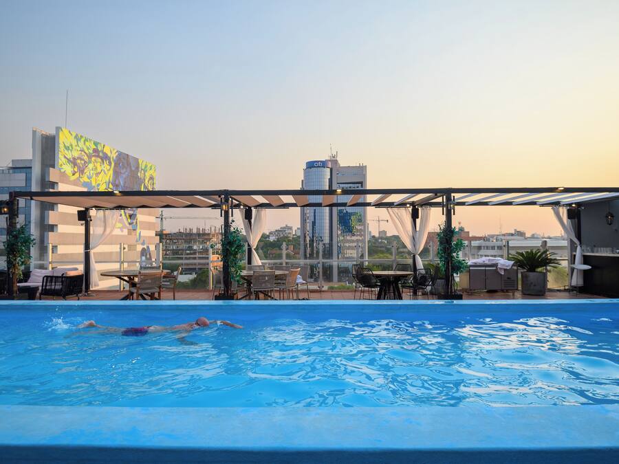 Una piscina en la azotea con vistas al perfil urbano, incluyendo un edificio con un letrero 'citi'.