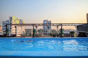 Una piscina en la azotea con vistas al perfil urbano, incluyendo un edificio con un letrero 'citi'.