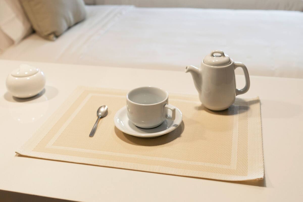 A neatly arranged breakfast setup on a hotel room table with a bed in the background.