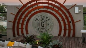 A rooftop patio with a circular metal art piece, outdoor seating, and potted plants. - Five Hotel & Residences (Asunción)