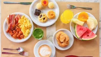 Una escena de desayuno con platos de comida, un vaso de zumo de naranja y una taza de café.