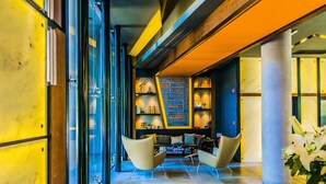 A modern lobby with a wooden floor, a reception desk, and a seating area with a bookshelf. - Five Hotel & Residences (Asunción)