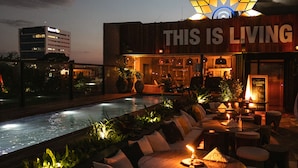 A rooftop bar with a pool, outdoor seating, and a sign that reads "THIS IS LIVING". - Five Hotel & Residences (Asunción)