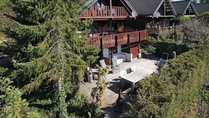 Eine Holzhütte mit einer Terrasse, umgeben von dichtem Wald.