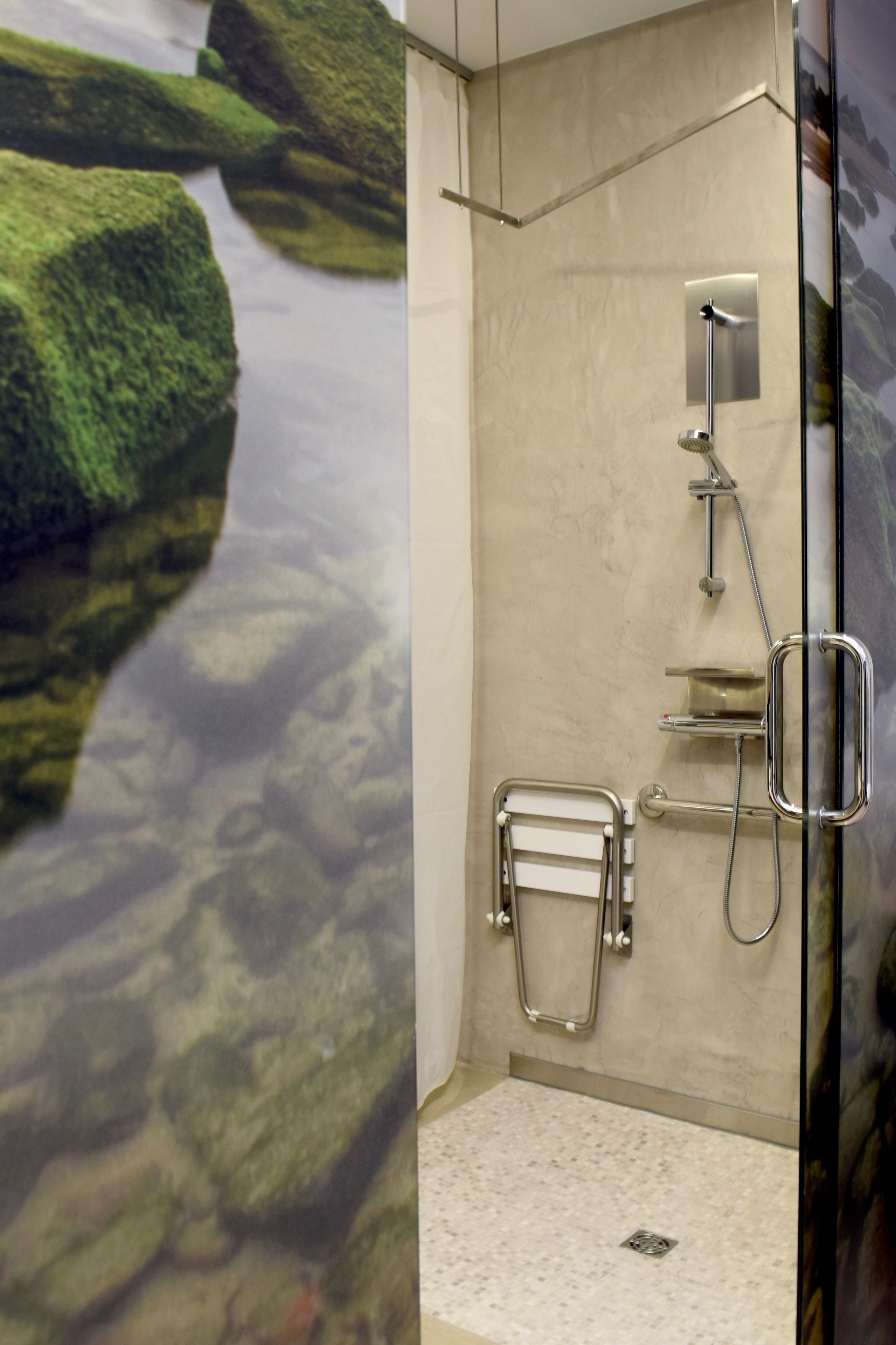 A modern bathroom with a glass shower enclosure, a built-in towel rack, and a visible drain.