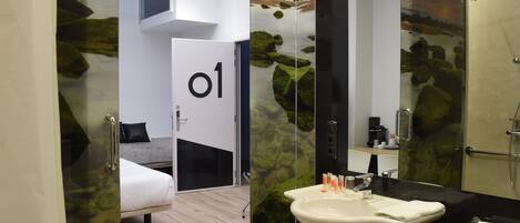 Un baño moderno con cabina de ducha de vidrio, un lavabo blanco y un espejo grande.