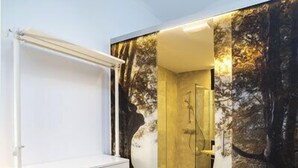 A modern bathroom with a glass-enclosed shower, a white vanity with drawers, and a wooden floor. - Hotel Zerupe (Zarautz)